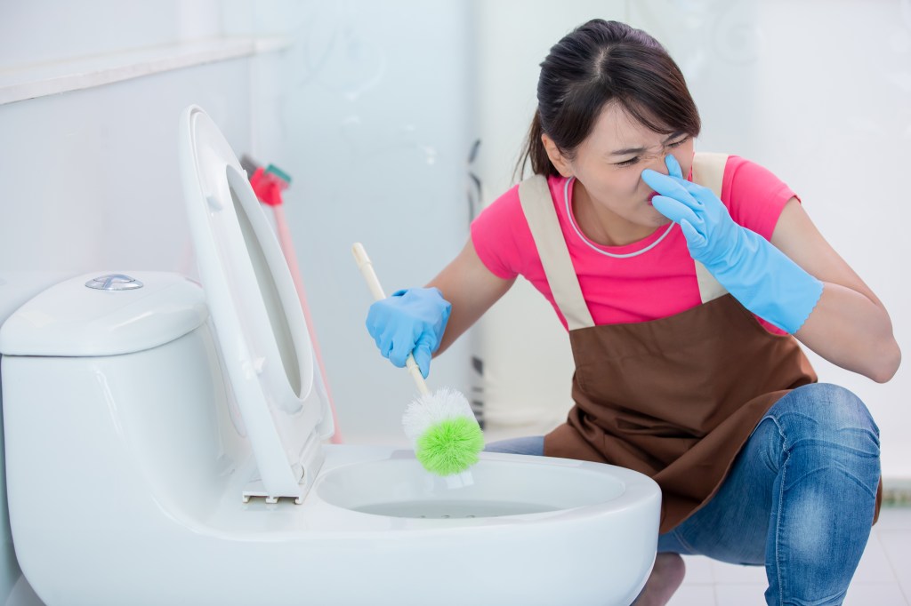 asian woman wipes toilet and feels stinky